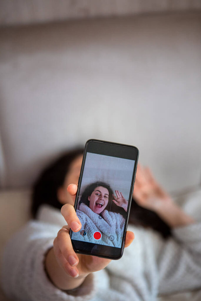 young happy woman taking selfie story laying down in bed - Foto, Bild