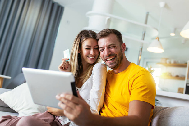 Щаслива молода пара купує онлайн з цифровим планшетом і кредитною карткою вдома
 - Фото, зображення