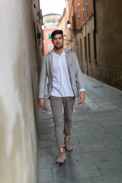 Красивый темноволосый итальянский парень в элегантной куртке в центре города. Высокое качество фото - Фото, изображение
