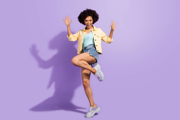 Photo of funny impressed woman dressed yellow jeans rising arms dancing isolated purple color background - 写真・画像