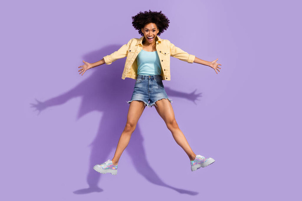 Photo of pretty excited woman dressed yellow jeans jumping high like star isolated purple color background - Fotó, kép