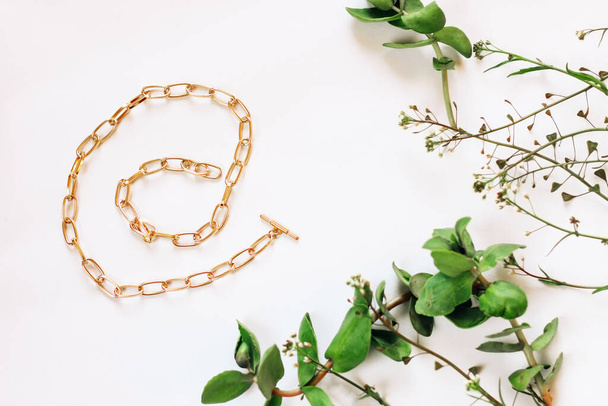 Fashionable jewelry chain with gold on a background with green plants. - Valokuva, kuva