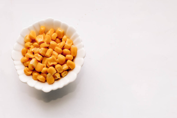 Canned corn for salad in a plate on a white table. - Foto, Imagem