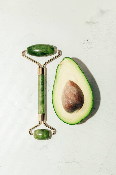 Grüne reife Avocado mit Jade-Gouacheschaber und Rollerball auf hellem Hintergrund. - Foto, Bild