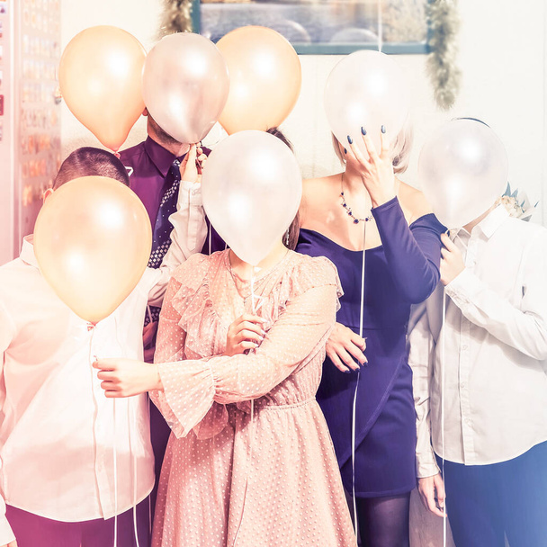 Μια οικογένεια που κρύβει τα πρόσωπά της πίσω από μπαλόνια. Χαρούμενη οικογενειακή φωτογραφία διακοπών. - Φωτογραφία, εικόνα