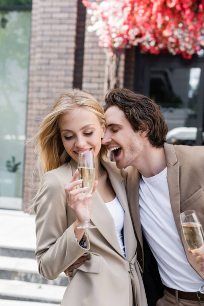 excited man near smiling brunette woman with champagne glass on urban street - Photo, Image