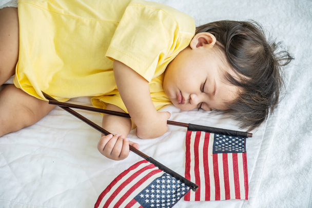 Lindo, Retrato de bebé pequeño o bebé durmiendo en la cama con comodidad, Ella está durmiendo con la celebración de la bandera americana, Adorable concepto de niño recién nacido, 4 de julio, Día de la independencia, concepto de día de la bandera - Foto, Imagen