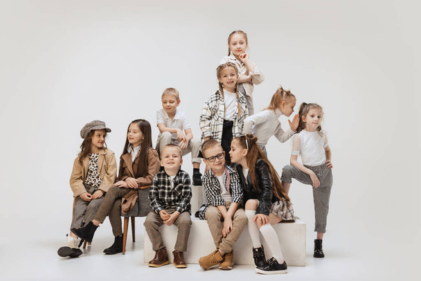 Ten happy smiling kids, little girls and boys in modern outfits posing on grey studio background. Beauty, kids fashion, education, happy childhood concept. - Foto, Imagen