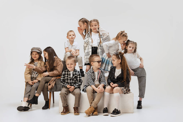 Ten happy smiling kids, little girls and boys in modern outfits posing on grey studio background. Beauty, kids fashion, education, happy childhood concept. - Фото, изображение