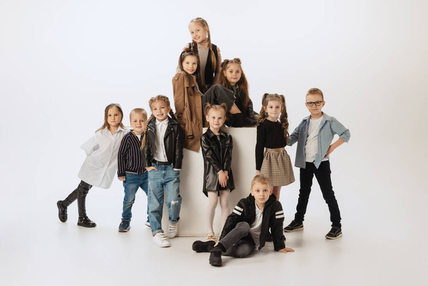 Group of happy smiling kids, little girls and boys in modern outfits posing on grey studio background. Beauty, kids fashion, education, happy childhood concept. - Фото, изображение