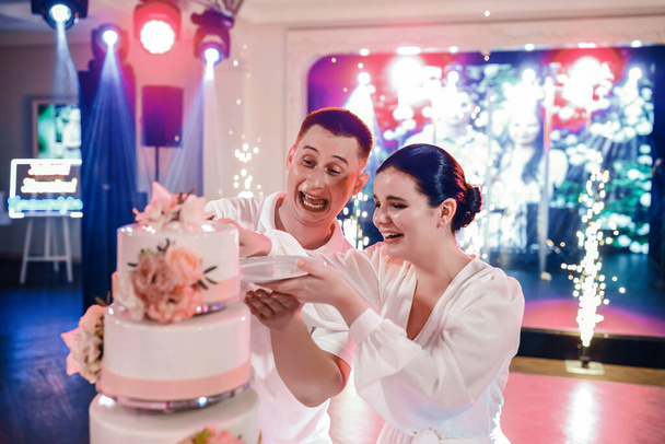 The wedding couple cuts the wedding cake with a festive vibe. The groom dares - Foto, Imagem