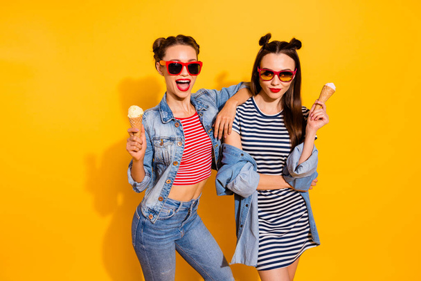 Portrait of two nice carefree brunette hair girls hold ice cream cone hug embrace isolated on yellow color background - Foto, Imagem