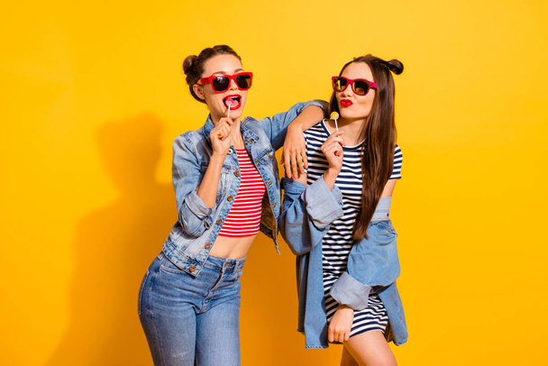 Photo of two ladies having fun lick candies wear denim clothes isolated on vibrant color background - Fotografie, Obrázek