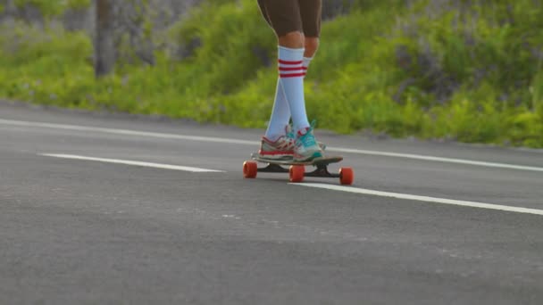 Portrait boy with a longboard on a beautiful road. Teenager skateboarding on city streets - Footage, Video