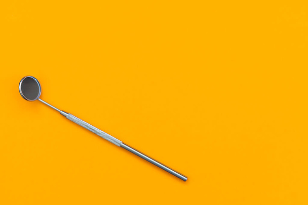 Dental mirror on an orange background. Medical tool - Foto, afbeelding