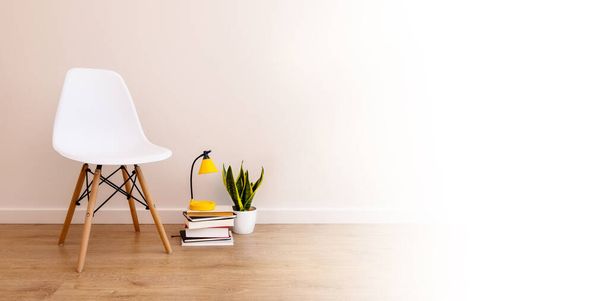 πανό με πάστα αντιγραφής, λευκό φόντο. Κενή καρέκλα δίπλα σε βιβλία, ξυπνητήρι και φυτό στο σπίτι - Φωτογραφία, εικόνα