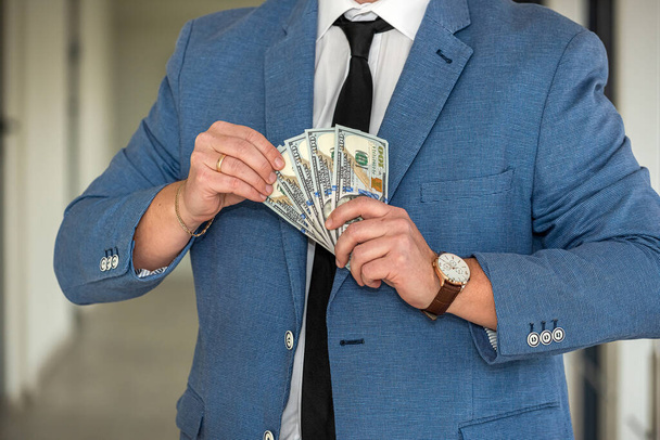 青いスーツの男ドル札のスタック。事業概念 - 写真・画像
