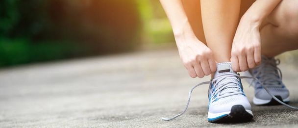 Running shoes. close up female athlete tying laces for jogging on road. Runner ties getting ready for training. Sport lifestyle. copy space banner. - Φωτογραφία, εικόνα
