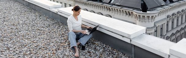 high angle view of barefoot woman working on laptop on rooftop, banner - Valokuva, kuva