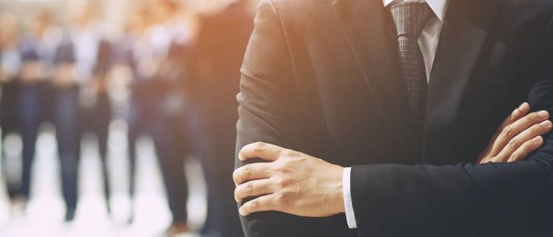Portret van een CEO zakenman staande hand cross arm succesvol business team in een klassiek zwart pak met werknemer op de achtergrond.  - Foto, afbeelding