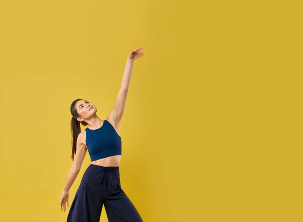 Stylish girl moving arm gracefully while dancing in studio. - Foto, imagen