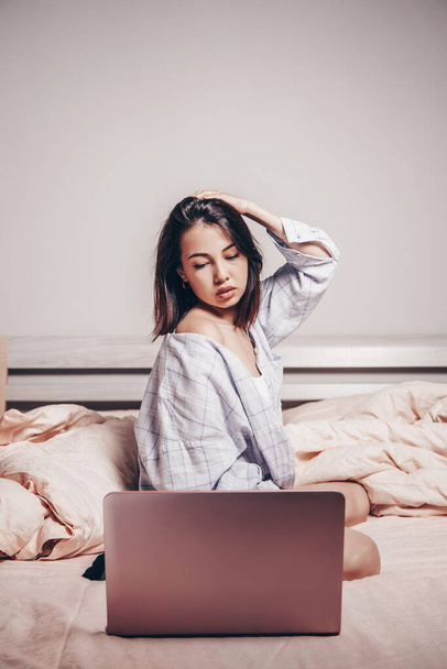 Nuori aasialainen webbikamera tyttö istuu kannettavan tietokoneen edessä. Hän kommunikoi ja näyttää viehätysvoimansa. alhainen tarkkuus, taiteellinen valokuvien käsittely - Valokuva, kuva