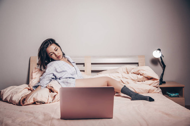 una joven asiática modelo webcam chica está tumbado en frente de un ordenador portátil con las piernas abiertas. disfruta y muestra sus encantos. baja profundidad de enfoque, enfoque selectivo. - Foto, Imagen