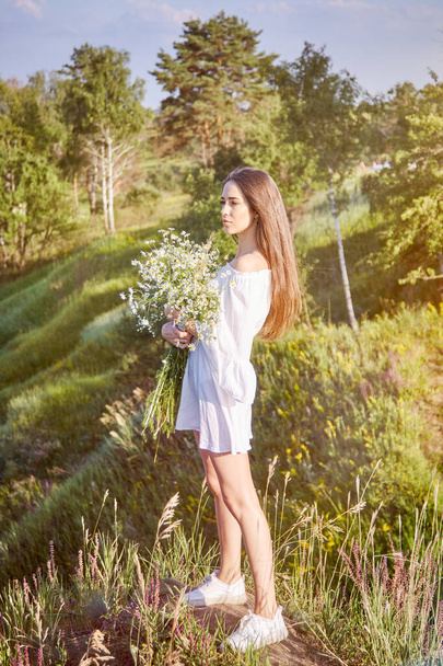 girl in a white dress walks in the field - Фото, зображення