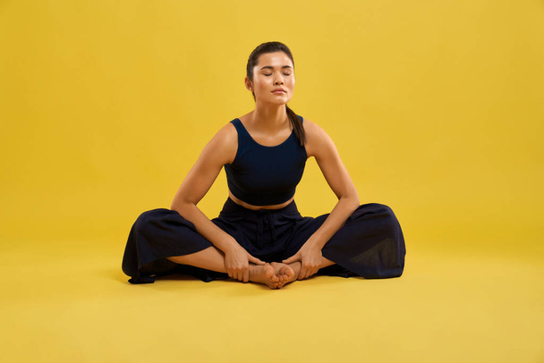 Attractive woman practicing yoga in butterfly II pose in spacious studio. - Φωτογραφία, εικόνα