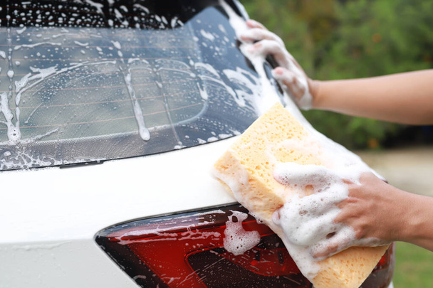 Menschen Arbeiter Mann hält Hand gelben Schwamm und Blasenschaumreiniger Fenster zum Waschen Auto. Konzept Autowäsche sauber. Lassen Sie Raum für das Schreiben von Nachrichten. - Foto, Bild