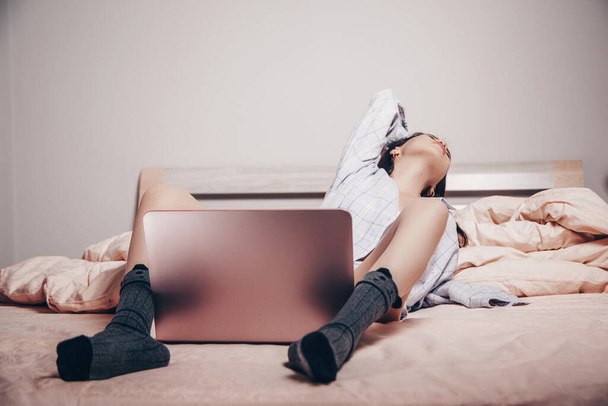 mladý asijský webkamera modelka dívka leží před notebookem s nohama roztaženýma. si užívá a ukazuje svůj šarm. nízká hloubka zaměření, selektivní zaměření. - Fotografie, Obrázek