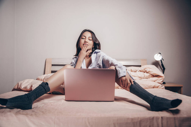 Молода дівчина з азіатських веб-камер сидить навпроти ноутбука з розстебнутими ногами. вона спілкується і показує свої чари. низька глибина фокусу, художня фотографія - Фото, зображення