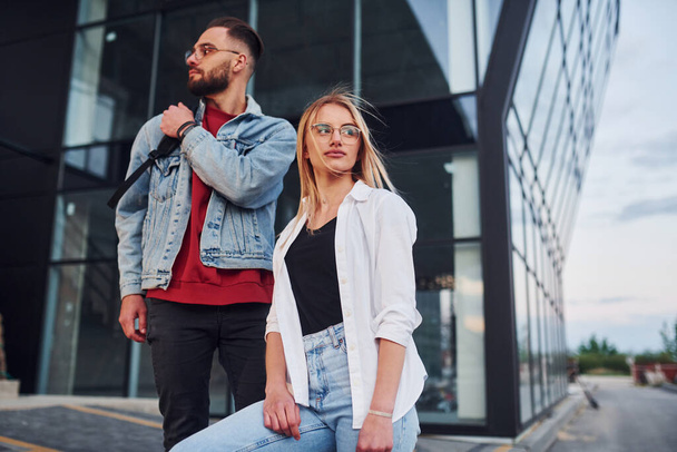 Young stylish man with woman in casual clothes outdoors together near business building. Conception of friendship or relationships. - Foto, Imagem