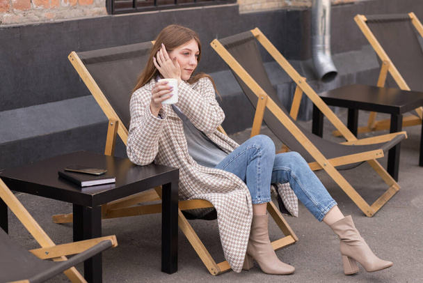 a woman with a cappuccino in a street cafe. blogging - 写真・画像