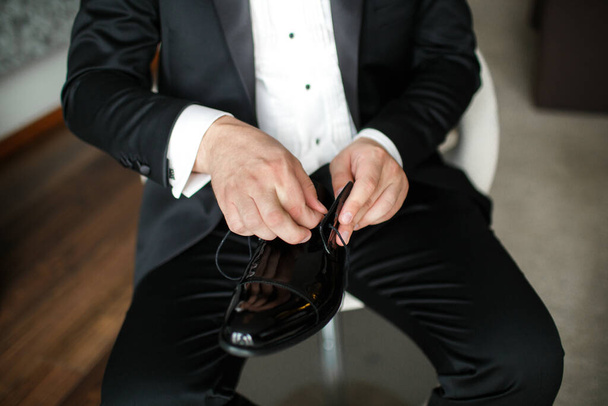 The groom fixes the laces on his shoes. - Foto, afbeelding