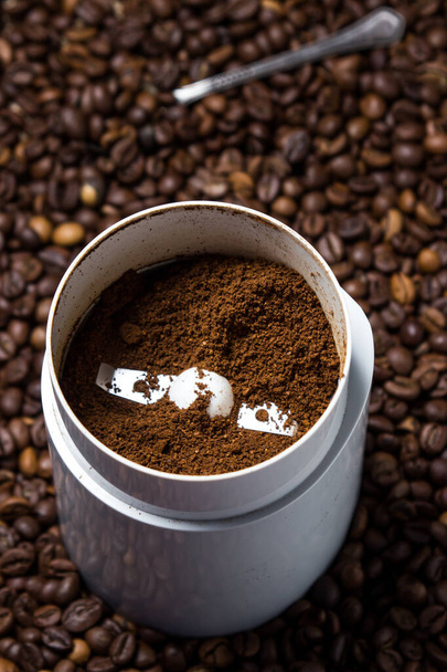 Mletá káva v mlýnku na kávu na pozadí kávových zrn. Čerstvá káva. - Fotografie, Obrázek