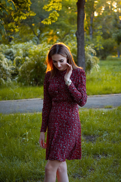 Attractive young woman enjoying her time outdoors in a park with sunset in the background. - Zdjęcie, obraz