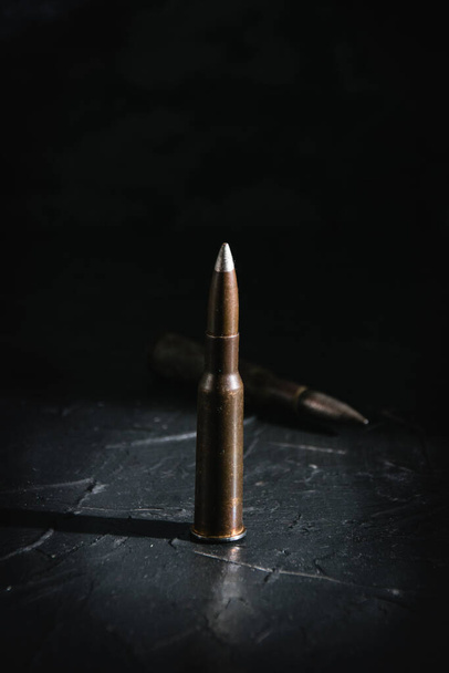 Cartridge on a dark background. The concept of modern armaments and wars. - Фото, изображение