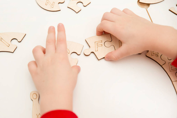 Juguete de madera 3D. Aprender letras en orden de alfabeto. Dedos de niño sostiene piezas de inacabados para montar rompecabezas. - Foto, Imagen