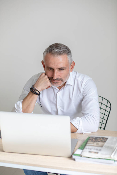 Thoughtful man looking at laptop touching face with fist - Foto, immagini