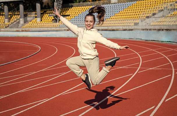 Energetic girl child jump at athletics track physical education outdoors, sport - Foto, imagen