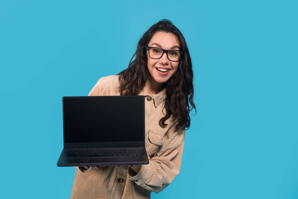 Örülök meglepett vicces fiatal európai hölgy tanuló szemüvegben mutatja laptop üres képernyőn - Fotó, kép