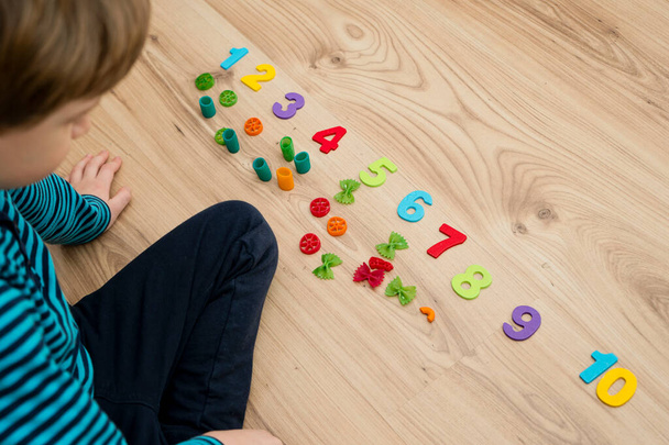 Math with fun. Calculation and marking of uncooked pasta with colored natural wood numbers. Do-it-yourself game. Play at home. The way of learning. - Foto, immagini
