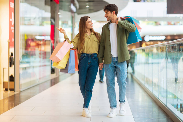 Customers Couple Shopping Walking Carrying Shopper Bags In Modern Mall - 写真・画像
