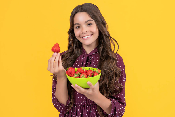 glad teen child hold strawberry bowl on yellow background - Foto, Imagen
