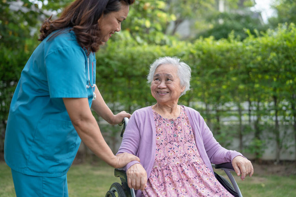 Doctor caregiver help and care Asian senior or elderly old lady woman patient sitting on wheelchair at nursing hospital ward, healthy strong medical concept - Foto, imagen