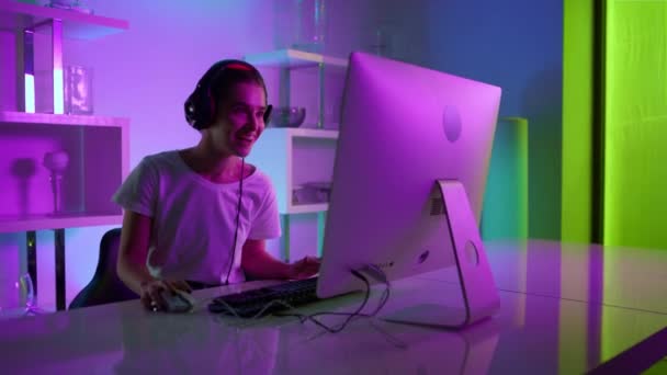 Cyber streamer che parla online con il primo piano del team. Giocatore gioioso al neon in cuffia - Filmati, video