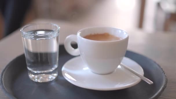 Fehér csésze kávé az asztalon egy pohár vízzel, 4k videó - Felvétel, videó