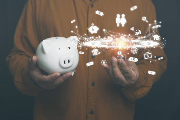 Businessman holding light bulb and white piggy bank with business, and financial icons on hands. innovation ideas and inspiration saving money to the future. Banking, financial, and save money concept. - Foto, Bild
