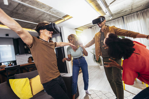 Cheerful friends having fun with VR in home interior - Foto, afbeelding